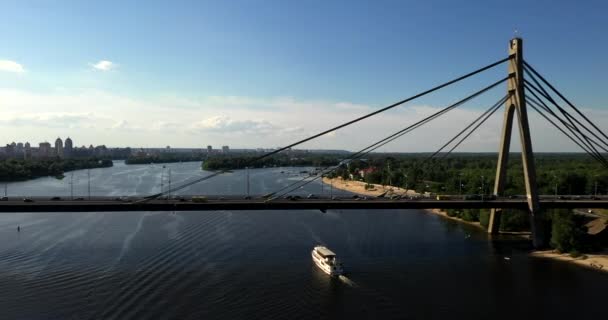 ドローンビュー映像トラフィックは、車がキエフで運転している橋にまっすぐ行きます。カメラはまっすぐ向いている、そして船は近くで航行している - 映像、動画