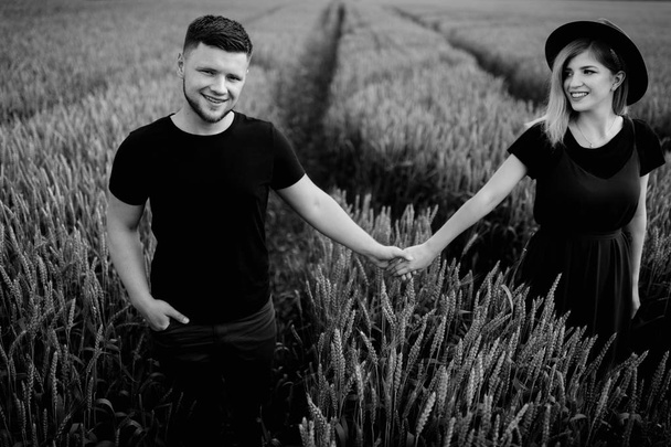 Beautiful young couple walking  on wheat field - Фото, зображення