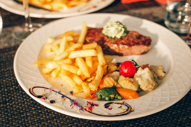 Όμορφα διακοσμημένο πιάτο με μπριζόλα Cafe de Paris με βούτυρο βοτάνων και τηγανητές πατάτες - Φωτογραφία, εικόνα
