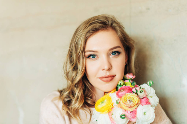 Retrato de una hermosa mujer joven sosteniendo coloridas flores de buttercup
 - Foto, imagen