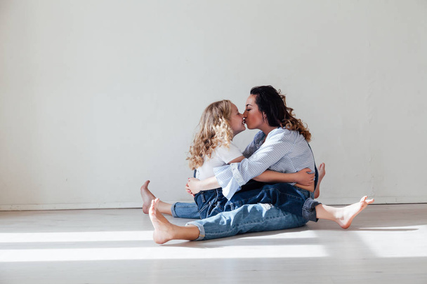 Mamá y su hija juegan abrazos en casa en el suelo
 - Foto, Imagen