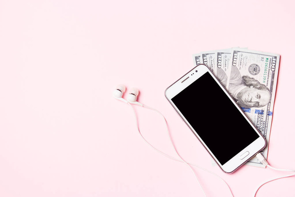 Téléphone portable avec écouteurs et argent sur fond rose. Concept de paiement et d'épargne
. - Photo, image