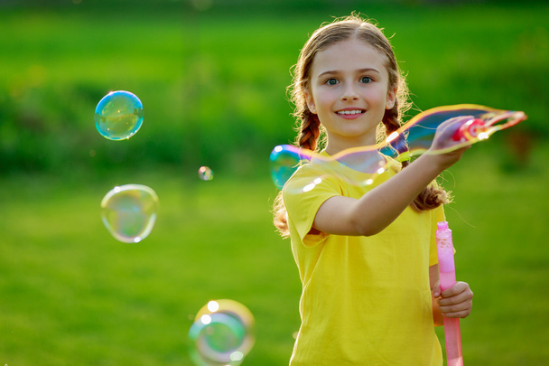 Summer joy, young girl playing with soap bubbles - Photo, Image