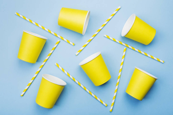 Yellow paper cups and yellow-white straw on blue background. Top - Fotoğraf, Görsel
