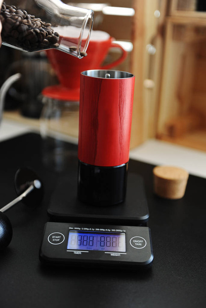 Red manual coffee grinder on electronic scale with timer. Alternative brewing and specialty concept - Photo, Image