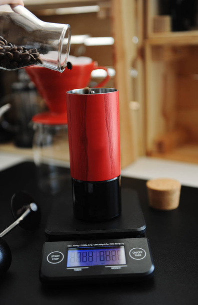 rote manuelle Kaffeemühle auf elektronischer Waage mit Zeitschaltuhr. Alternatives Brau- und Spezialitätenkonzept - Foto, Bild