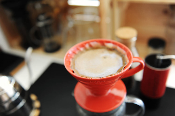 Kahvin valmistusprosessi. Punainen keraaminen tiputin lähikuva. Kukkivat. Erikoiskäsite
 - Valokuva, kuva