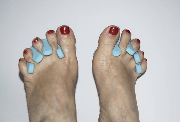 Piedi di donna con unghie dipinte e dita separate da spugne blu pedicure
 - Foto, immagini