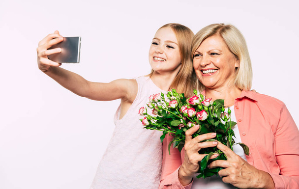 Family holidays and celebrations. Close up photo of happy grandmother and granddaughter in good and fun mood isolated together on white background. - Zdjęcie, obraz