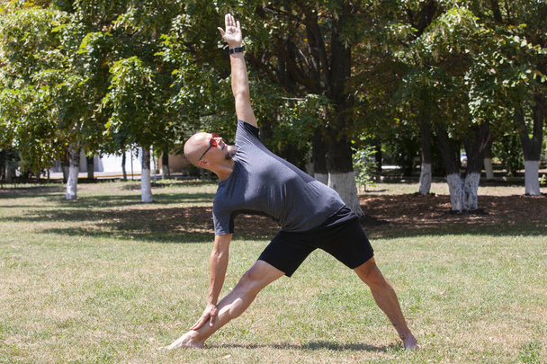 Man exercising in park. Smiling caucasian male doing core workout on grass. - Fotó, kép