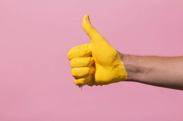 mão masculina mostrando sinal polegar para cima com tinta que flui para baixo em um fundo colorido. ideia criativa, conceito criativo, gesto "classe
" - Foto, Imagem