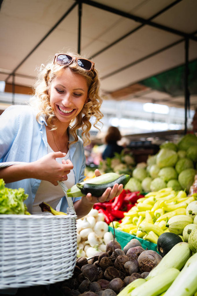 Picture of happy woman at marketplace buying vegetables - Foto, afbeelding