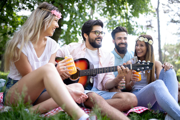 Summer, vacation, music and recreation time concept. Cheerful friends have picnic outdoor. - Fotografie, Obrázek