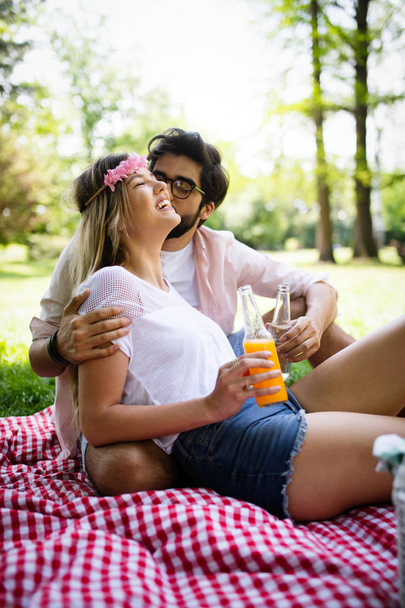 Happy young couple enjoying picnic in park outdoor - Фото, изображение