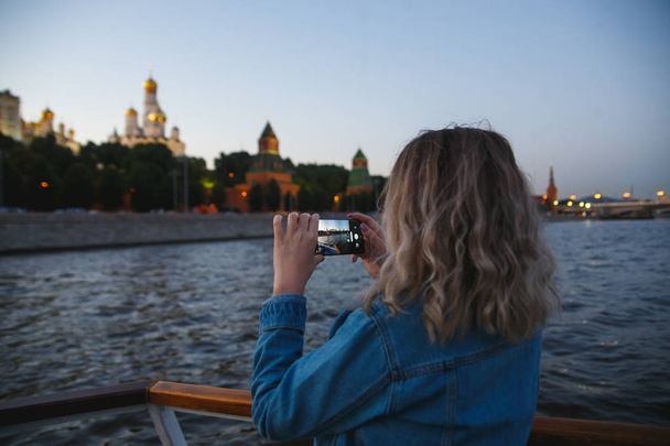 Woman tourist taking pictures on mobile phone during the boat trip on the Moscow river on the background the Kremlin. Travel to Russia concept - Φωτογραφία, εικόνα