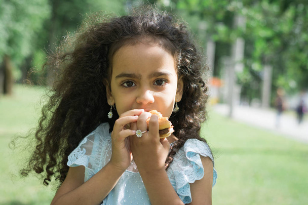 child tries a hamburger or cheeseburger closeup - Фото, зображення