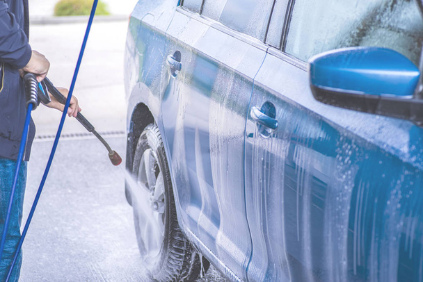Lavado manual del coche con agua a presión en el lavado del coche exterior.Limpieza del coche con agua de alta presión
. - Foto, imagen