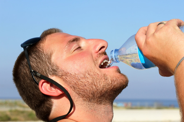 ένας άνθρωπος που είναι διψασμένοι ανυπόμονα να πίνει νερό από πλαστικό μπουκάλι - Φωτογραφία, εικόνα