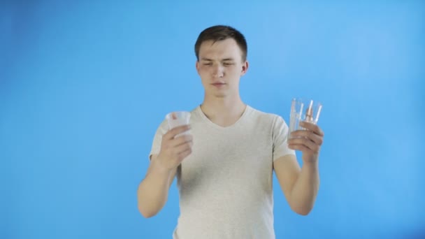 青の背景にプラスチックとガラスのカップと若い男の活動家 - 映像、動画