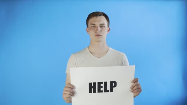 Junger Mann Aktivist mit HELP-Poster auf blauem Hintergrund - Filmmaterial, Video