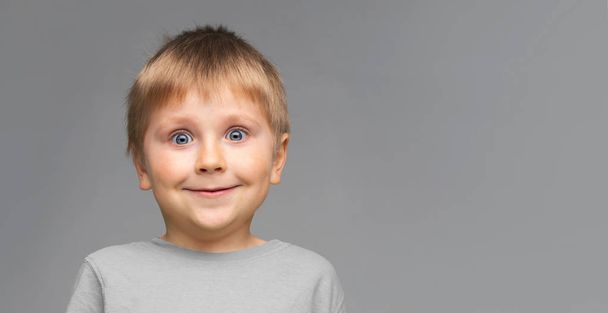 Portrait of happy smiling boy. Attractive kid in studio over grey background - Foto, Imagem