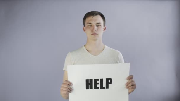 Junger Mann Aktivist mit HELP-Poster auf grauem Hintergrund - Filmmaterial, Video