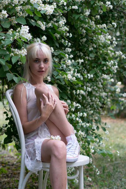 retrato de una joven hermosa chica de pie en un arbusto de jazmín
 - Foto, imagen