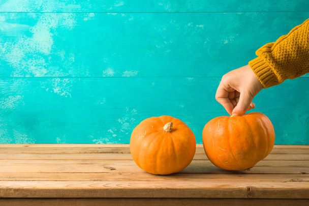 Autumn background with pumpkin on wooden table and woman hand. - Foto, Imagem