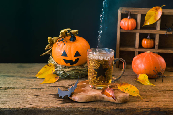 Halloween holiday concept with cup of tea and pumpkin decoration - 写真・画像