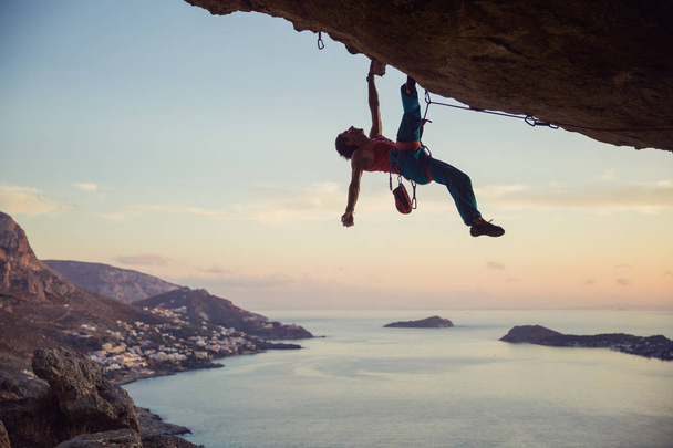 Jonge man worstelen om uitdagende route op de klif te beklimmen - Foto, afbeelding