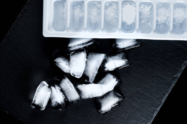 cubitos de hielo congelados y formas para un refrigerador en un plato de piedra o
 - Foto, imagen