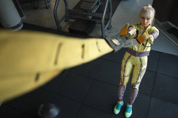 Вид сверху на тренирующуюся блондинку с фитнес-лямками trx в тренажерном зале
 - Фото, изображение