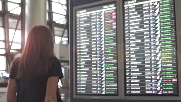 Una mujer en el aeropuerto mira el tablero de información de las salidas
 - Metraje, vídeo