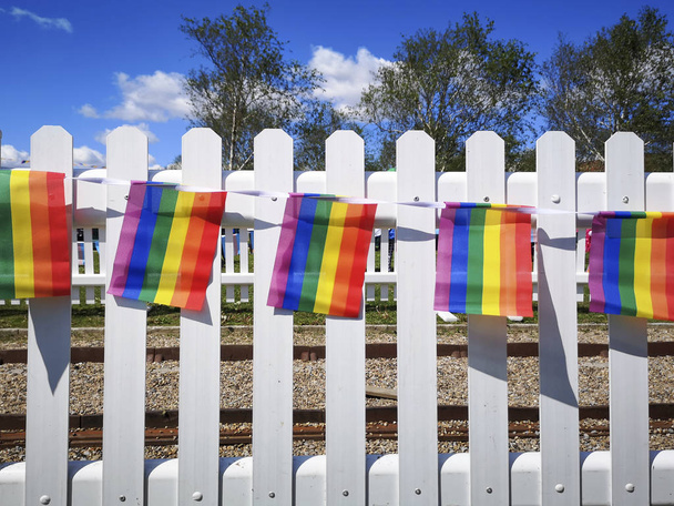 Rainbow liput Gay Pride Parade ripustettu valkoinen aita aurinkoisena päivänä sininen taivas tausta - tueksi monimuotoisuutta ja vaihtoehtoisia elämäntapoja yhteisössä
. - Valokuva, kuva