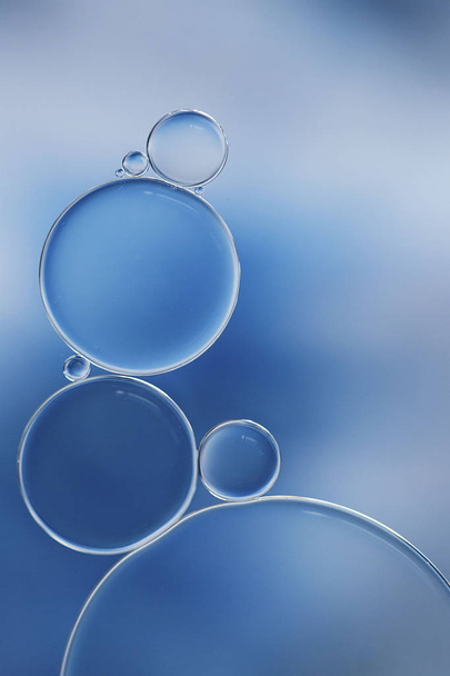 Makro von Öl- und Wasserblasen, die ein wissenschaftliches Bild der Zelle und Zellmembran mit einem blau-weißen Gradienten und in einem horizontalen Format erzeugen. - Foto, Bild