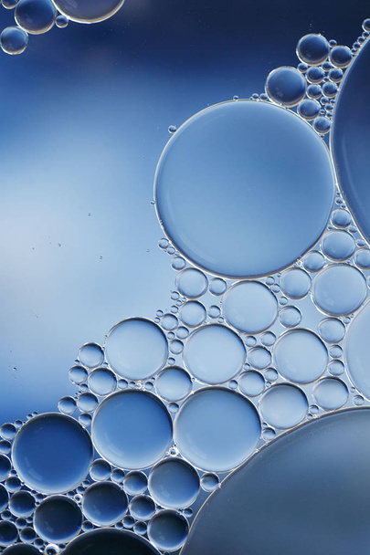 Μακρο του λαδιού και των φυσαλίδων νερού δημιουργώντας μια επιστημονική εικόνα της κυτταρικής και κυτταρικής μεμβράνης με μια μπλε και λευκή διαβάθμιση και σε μια οριζόντια μορφή. - Φωτογραφία, εικόνα
