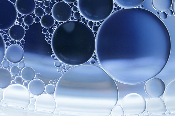 Macro de burbujas de aceite y agua creando una imagen científica de la célula y la membrana celular con un gradiente azul y blanco y en un formato horizontal
. - Foto, Imagen
