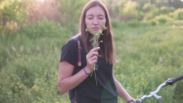 A woman sniffs yellow wildflowers. - Footage, Video