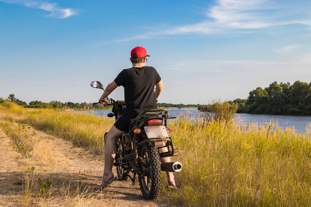 Їзда на мотоциклі паралельно річці в пошуках нового маршруту
 - Фото, зображення