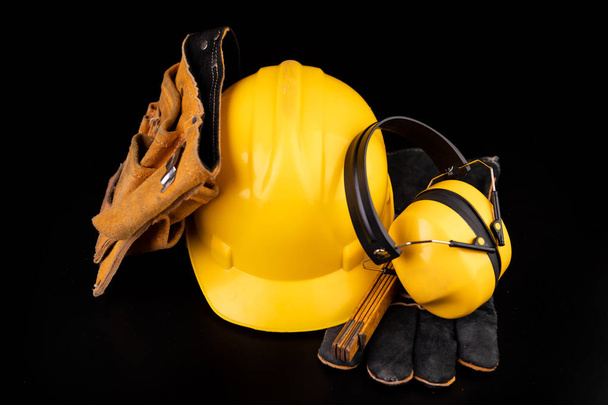 Helmet, gloves and scoop on a dark workbench. Safety and hygiene accessories for construction workers. Black background. - Foto, afbeelding