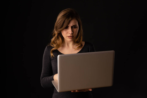 Нервова і засмучена молода жінка з ноутбуком отримує проблеми. Погані новини на екрані
. - Фото, зображення