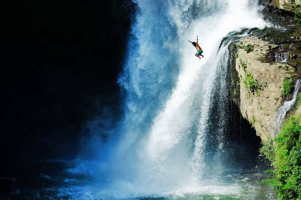 Jumping into the water. Man having fun at waterfalls in the nature. Bali, Indonesia - Foto, afbeelding