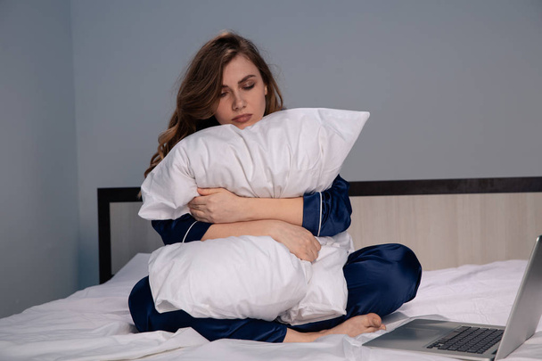 Üzgün kadın evde yatakta oturan ve izole bir yastık kucaklar. Uykusuzluk kavramı. - Fotoğraf, Görsel