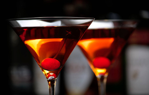 Cropped manhattan drinks with cherry with bar in the background - Fotó, kép