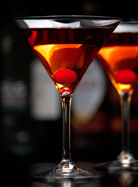 Cropped manhattan drinks with cherry with club in the background - Photo, Image