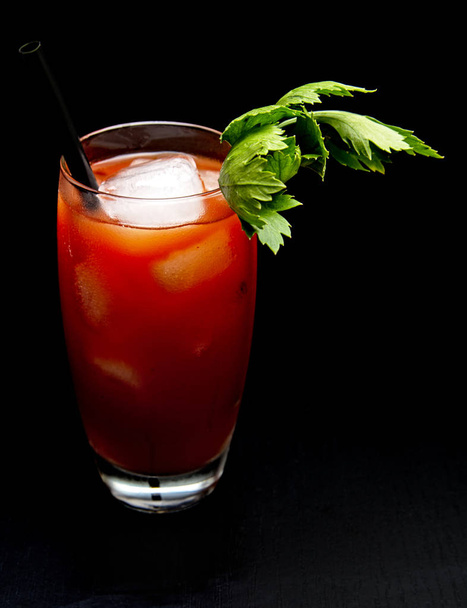 Bloody Mary with ice cubes with celery isolated on black - Photo, image