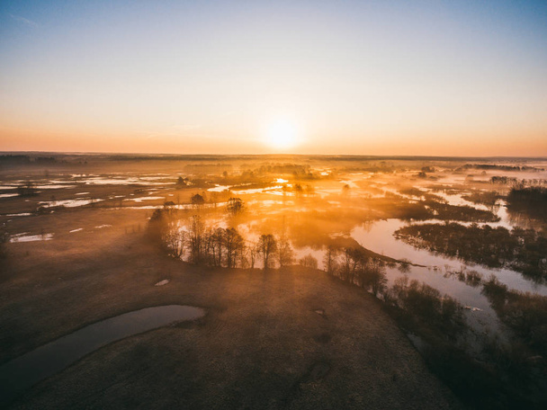 Sunrise over spring meadow. Spring aerial landscape. Spring sunrise over green forest and field with river and fog. - Photo, Image