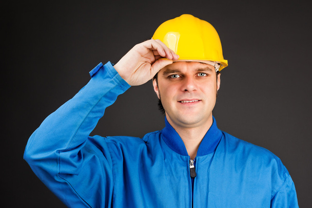 Young construction worker with his hand on hard hat brim - Fotoğraf, Görsel