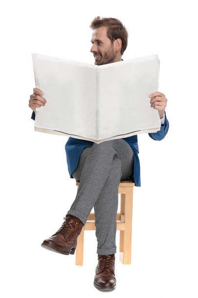Оптимистичный случайный парень держит газету и смотрит в сторону
 - Фото, изображение
