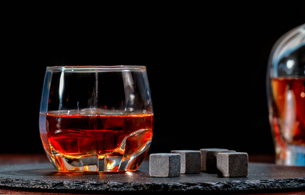 Glass of whiskey with black chilling cubes - Foto, Imagem